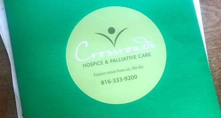 Photo: Green folder with Crossroads Hospice & Palliative Care sticker on it